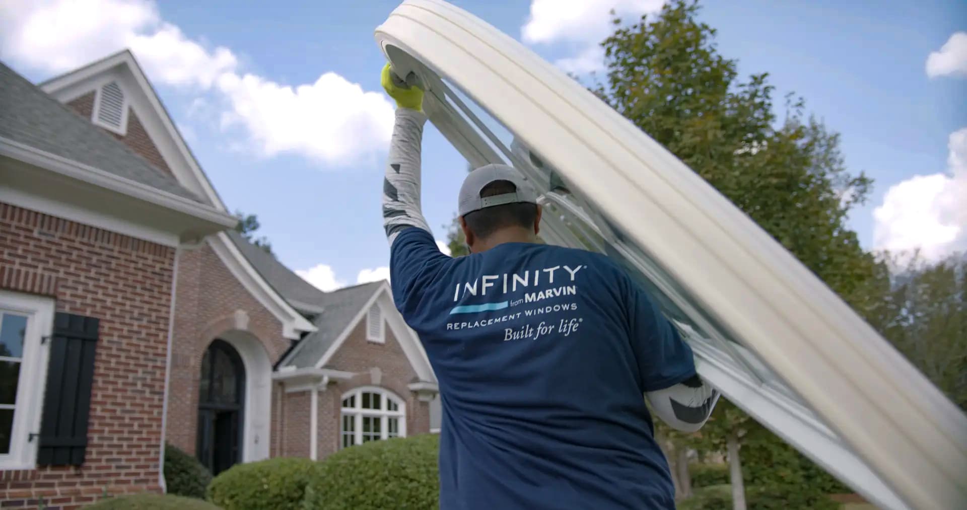 A man carrying an Infinity from Marvin window to a house.