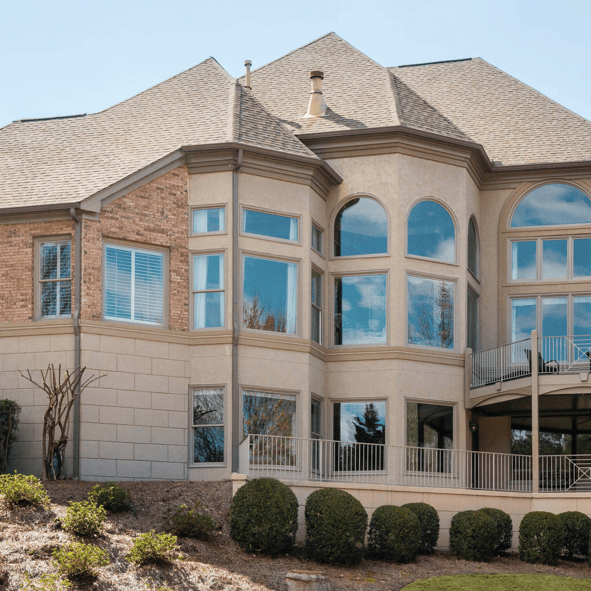 Brown stucco home exterior with large picture and round top windows.
