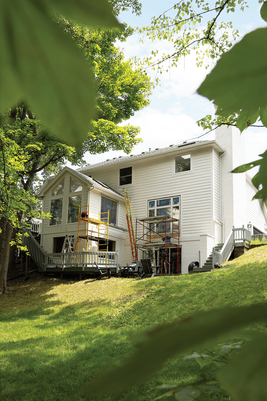 Backyard view of a white home exterior with scaffolding in front of windows during window installation..