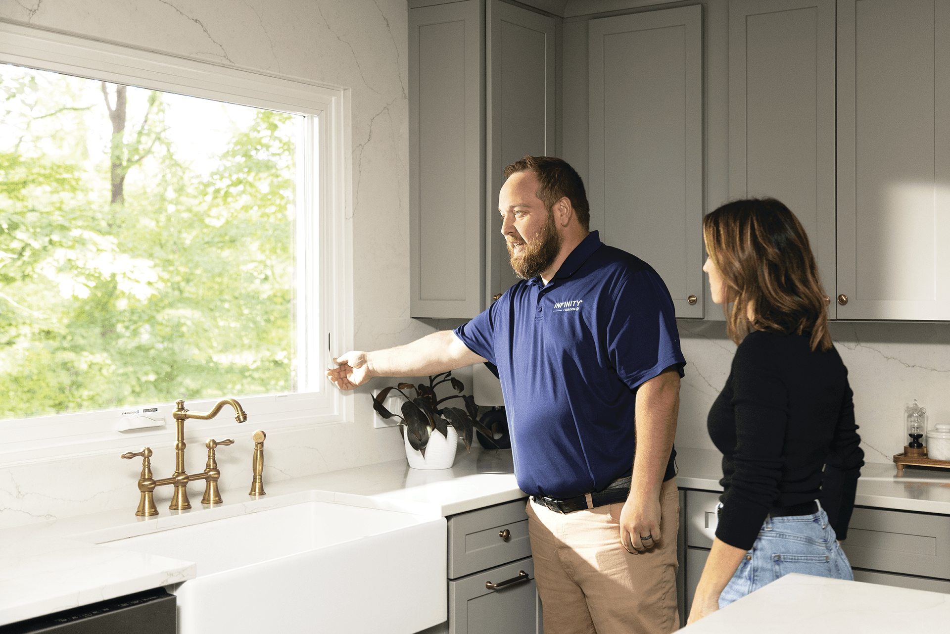 An Infinity by Marvin employee demonstrating how to open an awning window in a kitchen.